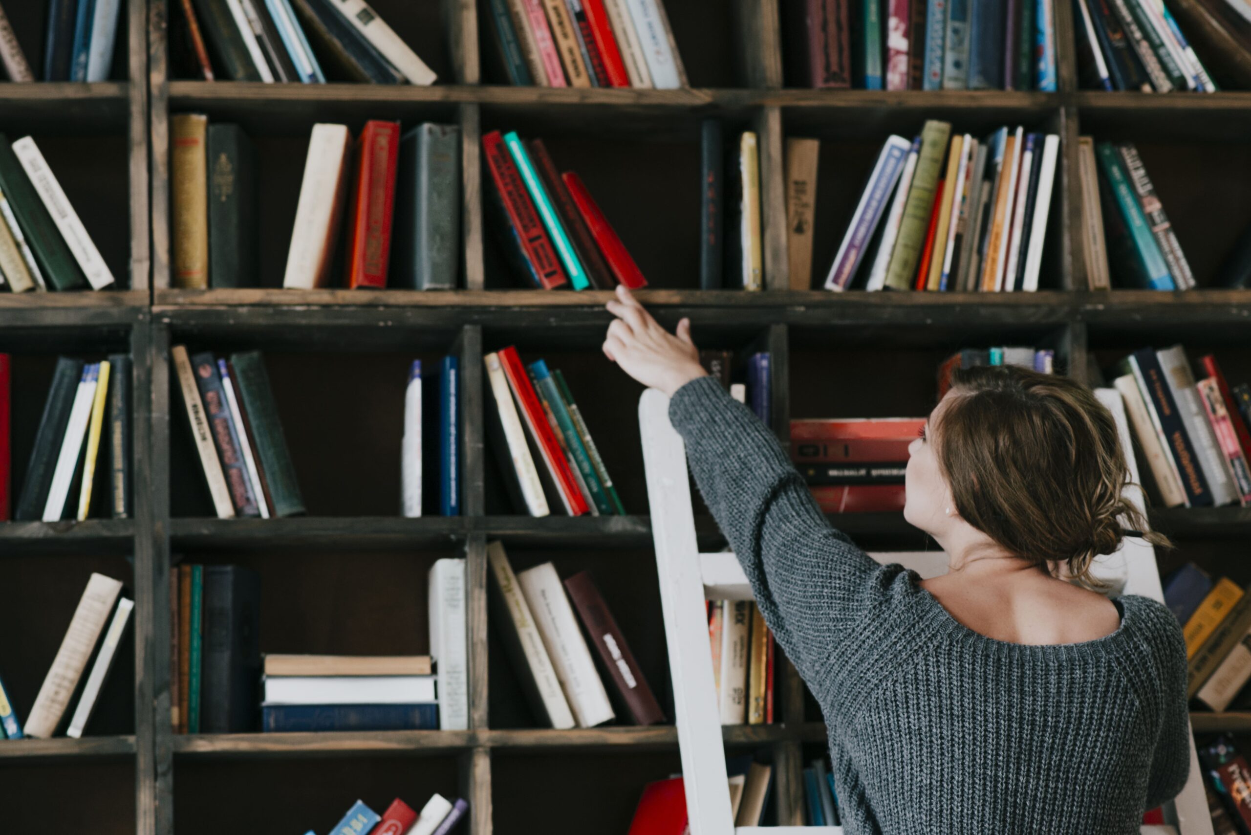 Femme choisissant un livre sur une bibliothèque